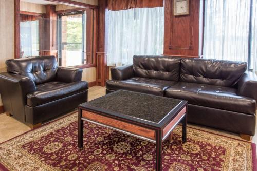 a living room with a leather couch and a coffee table at Baymont by Wyndham Muskegon in Muskegon