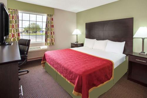 a hotel room with a large bed with a red blanket at Baymont by Wyndham Beloit in Beloit