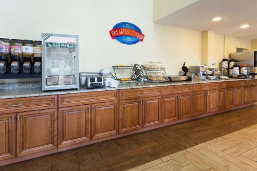a kitchen with wooden cabinets and a refrigerator at Baymont by Wyndham Beloit in Beloit