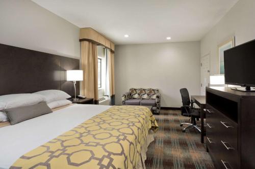 a hotel room with a bed and a flat screen tv at Baymont by Wyndham Bryan College Station in Bryan