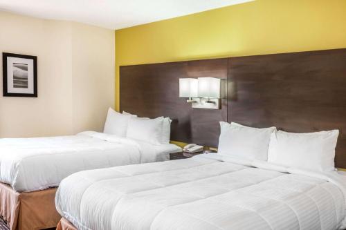 two beds in a hotel room with white pillows at Baymont by Wyndham Newark at University of Delaware in Newark