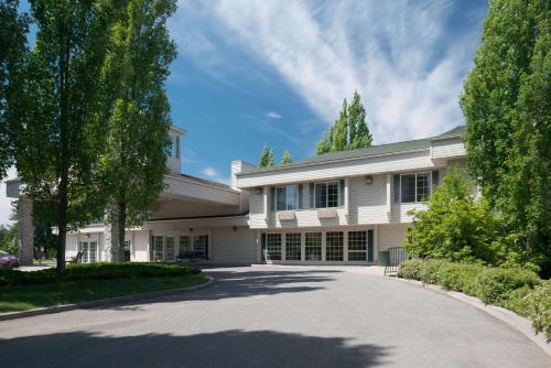 a large white house with a driveway at Baymont by Wyndham Coeur D Alene in Coeur d'Alene