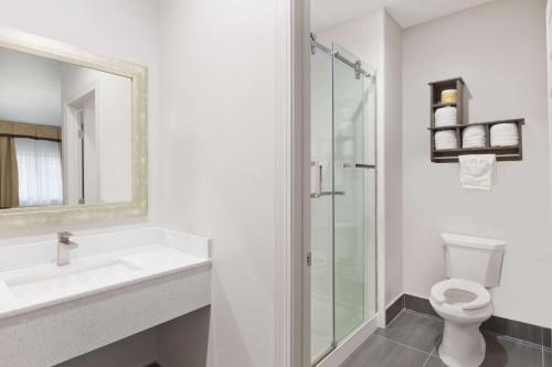 a bathroom with a toilet and a sink and a shower at Baymont by Wyndham Bryan College Station in Bryan