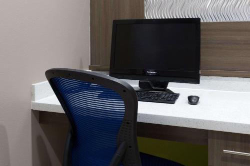 a desk with a computer monitor and a blue chair at Baymont by Wyndham Bryan College Station in Bryan