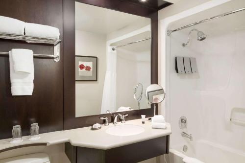 a bathroom with a sink and a toilet and a mirror at Ivey Spencer Leadership Centre, a Dolce by Wyndham in London