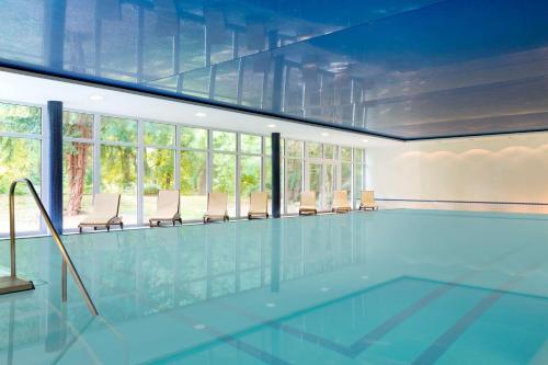 a large swimming pool with chairs and windows at Dolce by Wyndham Bad Nauheim in Bad Nauheim