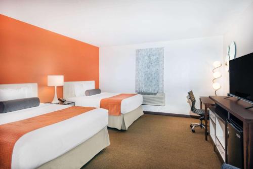 a hotel room with two beds and a television at Howard Johnson by Wyndham Quincy/ Boston in Quincy