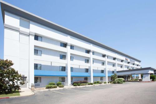 an exterior view of a large white building with blue accents at Baymont by Wyndham Texarkana in Texarkana