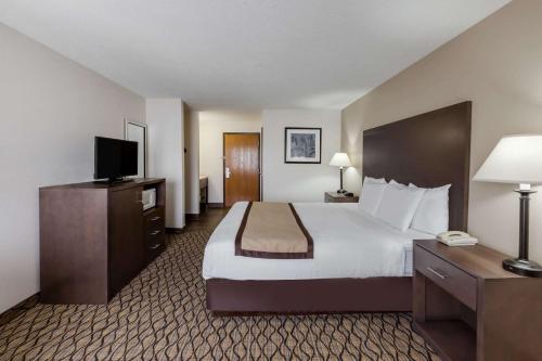 um quarto de hotel com uma cama e uma televisão de ecrã plano em Baymont by Wyndham Auburn em Auburn