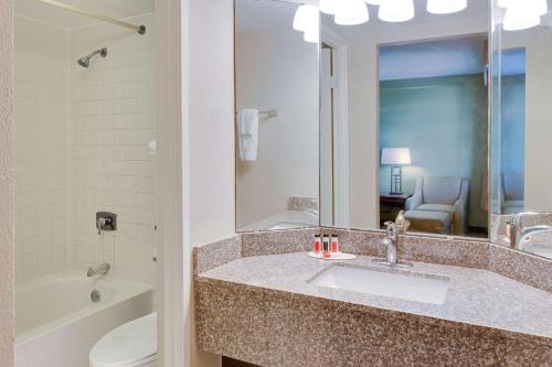 a bathroom with a sink and a toilet and a mirror at Baymont by Wyndham Jacksonville Orange Park in Jacksonville