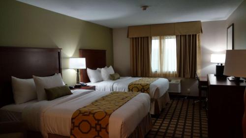 a hotel room with two beds and a desk at Baymont by Wyndham Oacoma in Oacoma