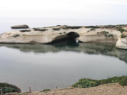 a body of water with a large rock in it at S'Ommu Ezza in Narbolia