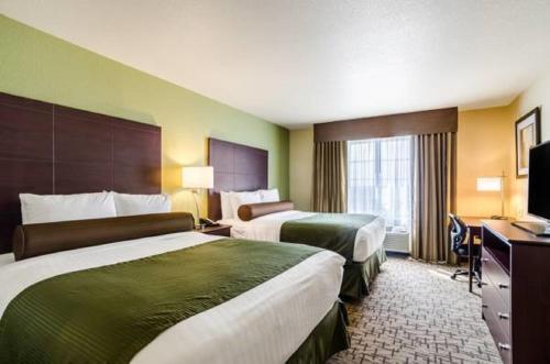 um quarto de hotel com duas camas e uma televisão em Cobblestone Inn & Suites - Vinton, LA em Vinton