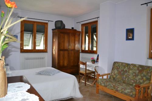 a bedroom with a bed and a couch and a chair at Agriturismo LA TAVERNA DEL NONNO in Borzonasca
