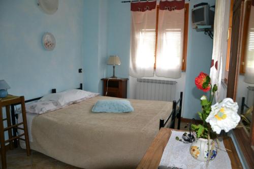 a bedroom with a bed and a table with flowers on it at Agriturismo LA TAVERNA DEL NONNO in Borzonasca