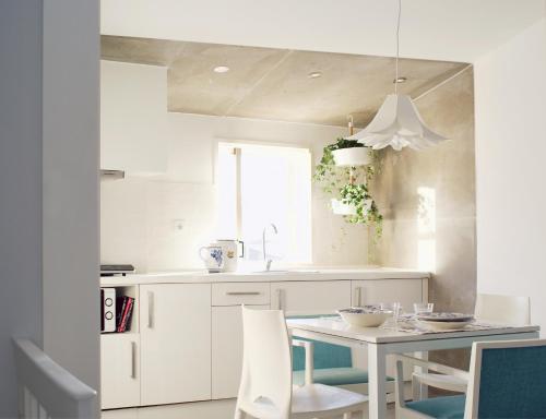 a white kitchen with a table and chairs at Casa de Cima in Coimbra