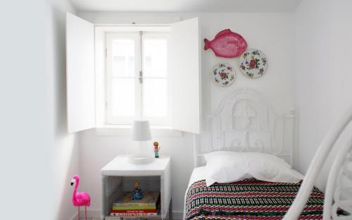 a white bedroom with a bed and a window at Casa de Cima in Coimbra