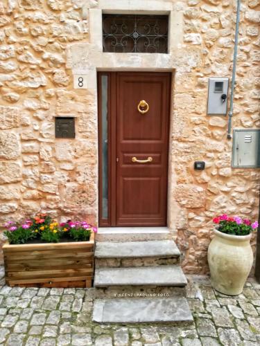 a wooden door on a stone building with flowers at La Casa di Giada in Modica
