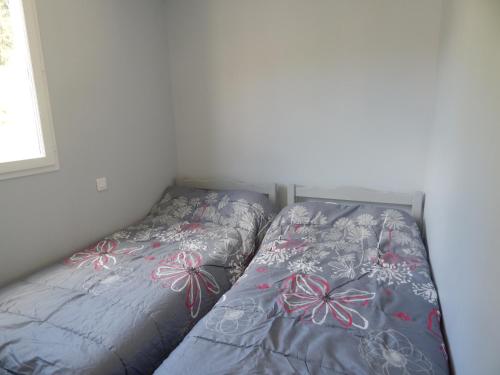 a bed in a room with a bedspread with flowers at Les maisonnettes de bonneval in Jaujac