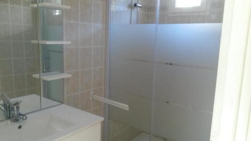 a shower with a glass door next to a sink at Les maisonnettes de bonneval in Jaujac