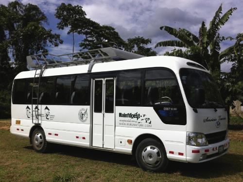 a white bus parked in a grass field at Posada Amazonas Lodge in Tambopata