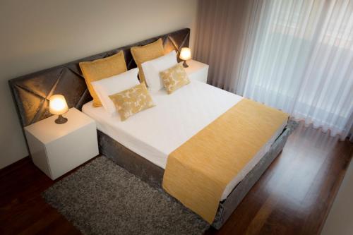 a bedroom with a bed with two lamps on it at Apartamento Latino Coelho in Póvoa de Varzim