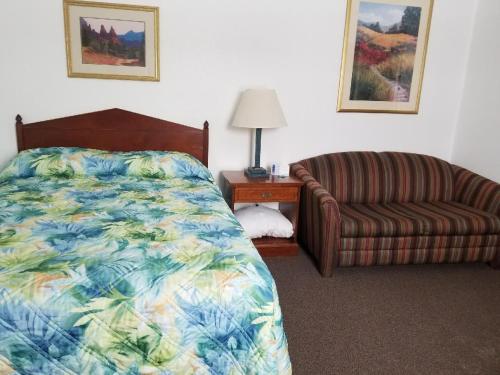 ein Schlafzimmer mit einem Bett, einem Sofa und einem Stuhl in der Unterkunft Howard's Motel in Glendo