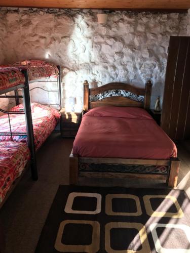 a bedroom with two beds and a stone wall at San Rafael de Guaquira in Aquitania