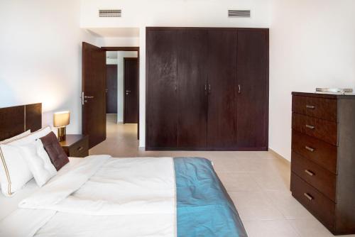 a bedroom with a large bed and a wooden cabinet at One Bedroom Apartment Dubai Fountain & Old Town View by Auberge in Dubai