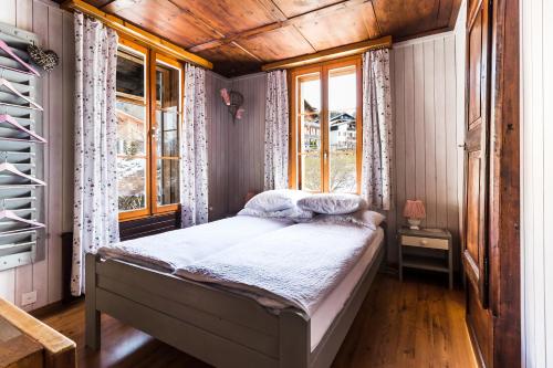 1 dormitorio con 1 cama en una habitación con ventanas en Ula's Holiday Apartments, en Beatenberg