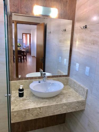 a bathroom with a sink and a mirror at Apartamento no Centro de Gramado in Gramado
