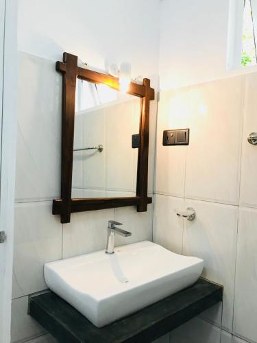 a bathroom with a white sink and a mirror at Sigiriya Rock Hide in Sigiriya