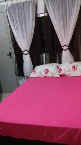 un lit rose avec des draps roses et des rideaux blancs dans l'établissement Casa Central, à Olímpia
