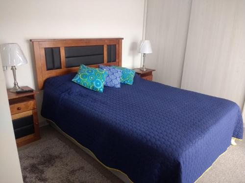 a bedroom with a blue bed with blue pillows at Departamento arica in Arica