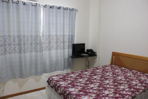 een slaapkamer met een bed en een raam met een gordijn bij Apartamento em Meia Praia in Meia Praia