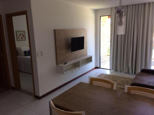 uma sala de estar com uma mesa e uma televisão na parede em Residence Iloa Resort em Barra de São Miguel