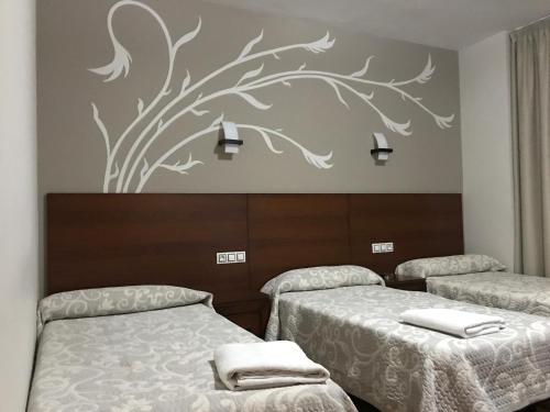 a room with two beds and a tree mural at Hostal Juli in San Justo de la Vega