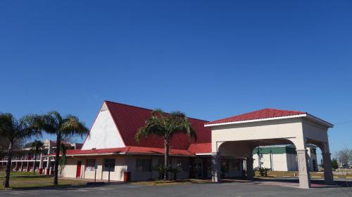 a gas station with a red roof and palm trees at Baton Rouge West Inn in Port Allen