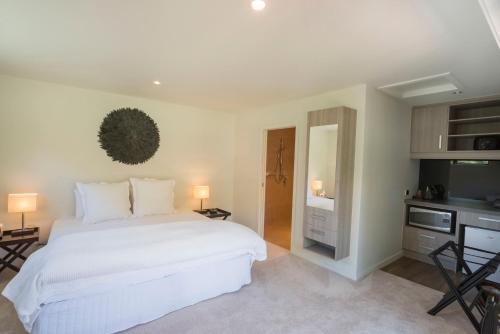 a bedroom with a large white bed and a television at Savana Estate in Poukawa