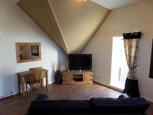 a living room with a couch and a tv at Church Street Apartments in Inverness