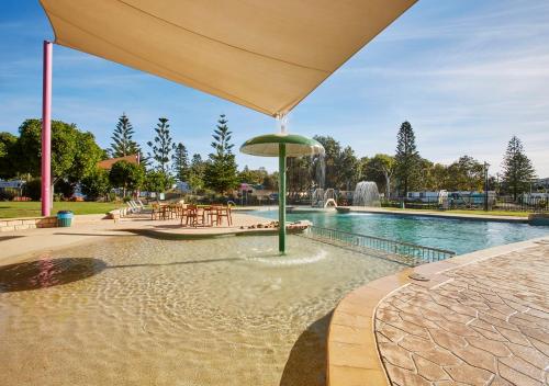 uma piscina com um guarda-sol ao lado de uma fonte em Toowoon Bay Holiday Park em The Entrance