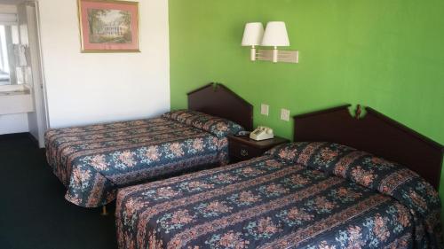 two beds in a hotel room with green walls at Baton Rouge West Inn in Port Allen