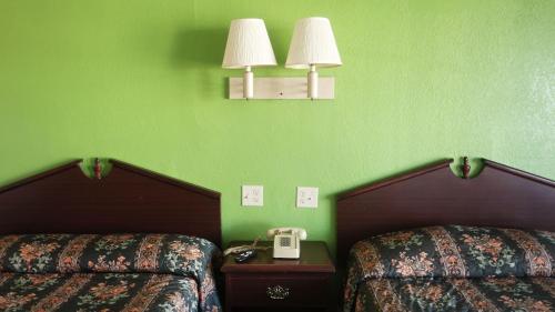 a green room with two beds and a phone on a table at Baton Rouge West Inn in Port Allen