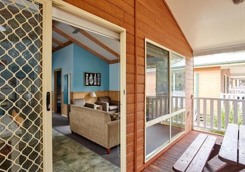 uma porta de vidro que dá acesso a uma sala de estar com um sofá em Toowoon Bay Holiday Park em The Entrance