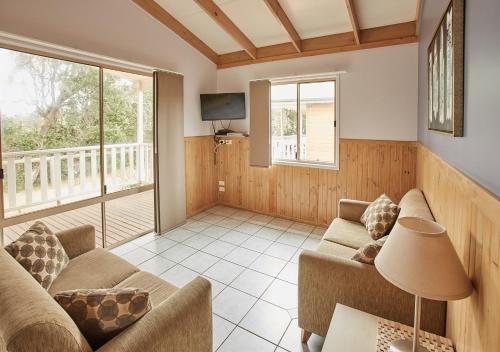 a living room with two couches and a tv at NRMA Toowoon Bay Holiday Park in The Entrance