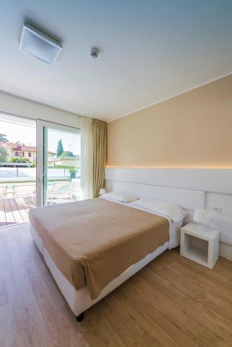 a bedroom with a large bed and a large window at Hotel Villa Katy in Bardolino