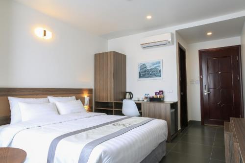 a bedroom with a large white bed and a desk at Punt Hotel in Hai Phong