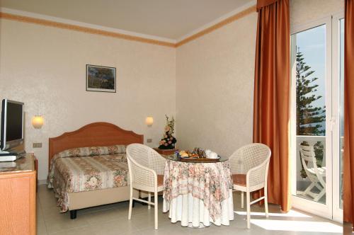 a hotel room with a bed and a table and chairs at Hotel Piccolo Lido in Bordighera