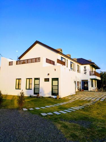 a large white house with green doors and a yard at Summer Homestay in Kenting