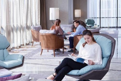 a group of people sitting in a room reading at Fraser Suites Dalian in Dalian